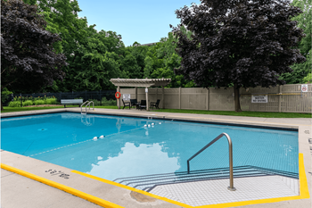 a swimming pool with trees in the background and a fence